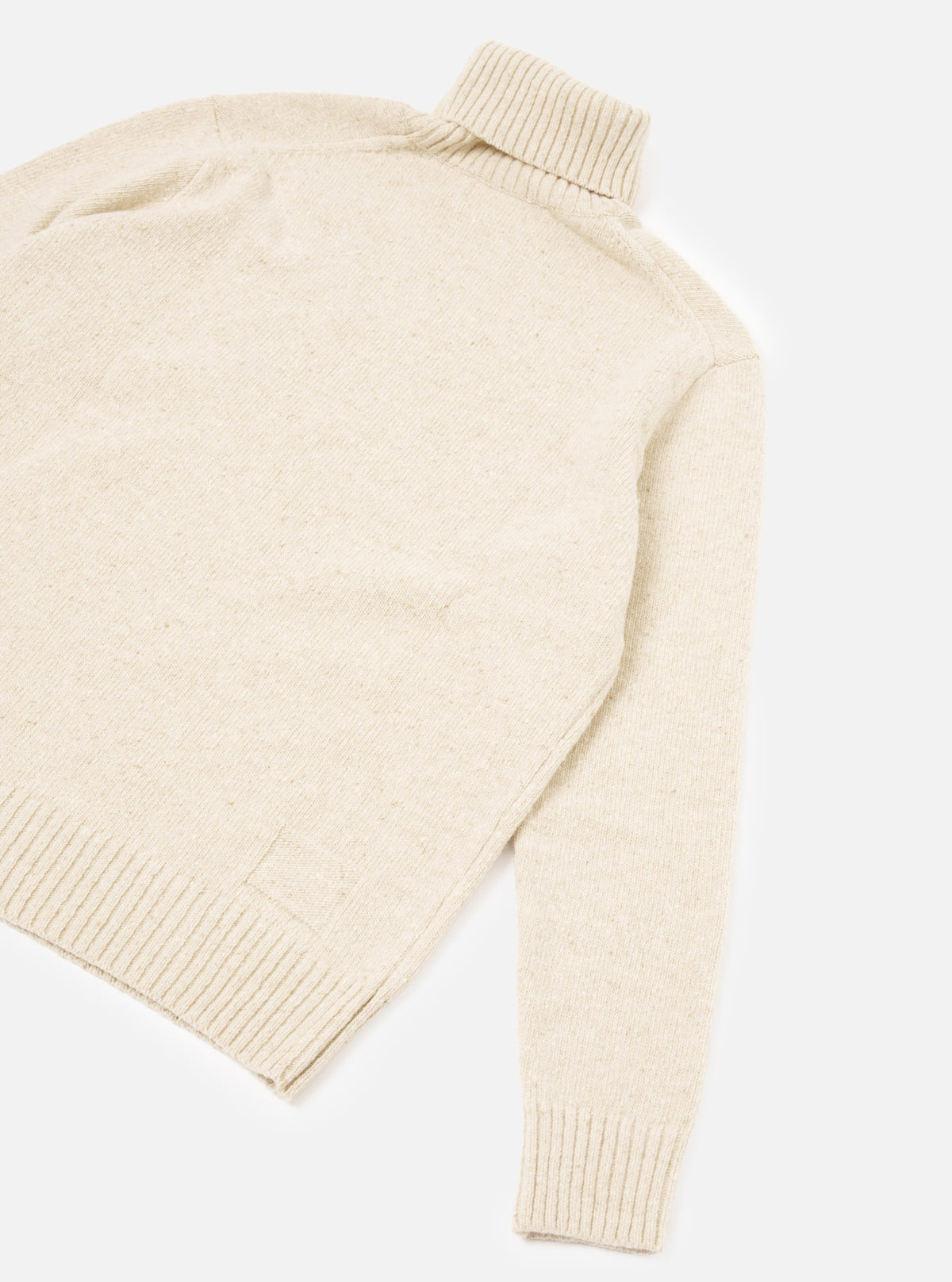 A back view of a model wearing the Fawn Wool Fleck Roll Neck on a plain background, highlighting the comfortable tailored drape, ribbed trim finishes, and natural fawn wool fleck knit fabric.