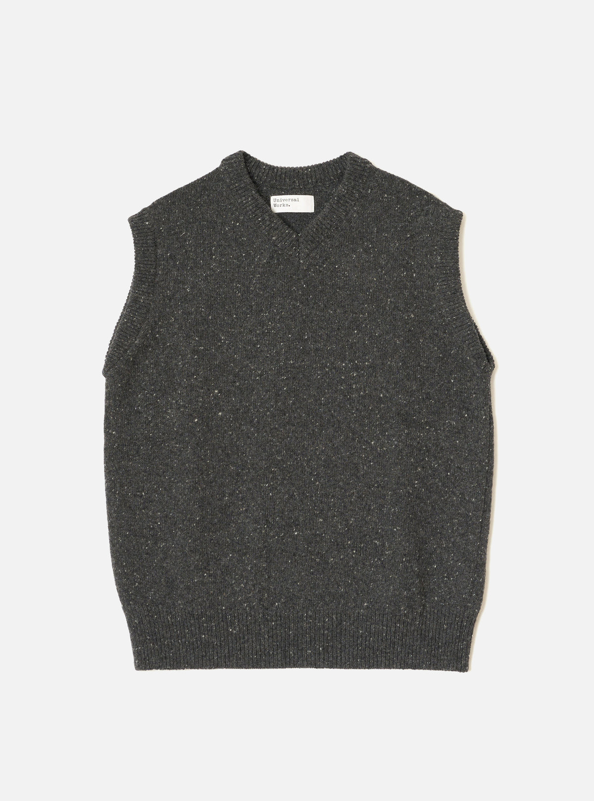 A model wearing the Black Wool Fleck Sweater Vest against a neutral studio backdrop. The sleeveless sweater vest features a classic V-neckline, ribbed hem, and subtle flecked recycled wool texture.