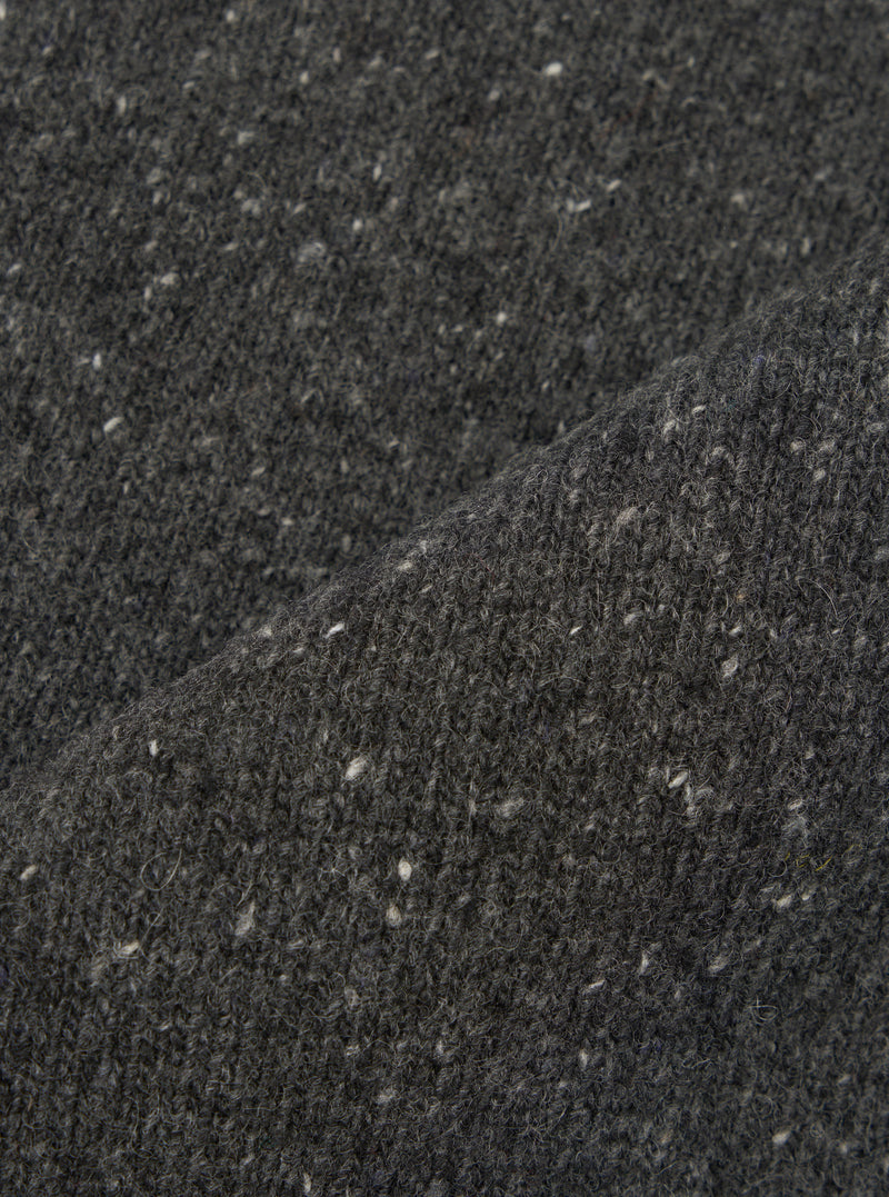 A close-up fabric swatch image of the Black Wool Fleck Sweater Vest material, illustrating the rich black shade, detailed knitted weave, and subtle contrasting fleck accents on a plain backdrop.