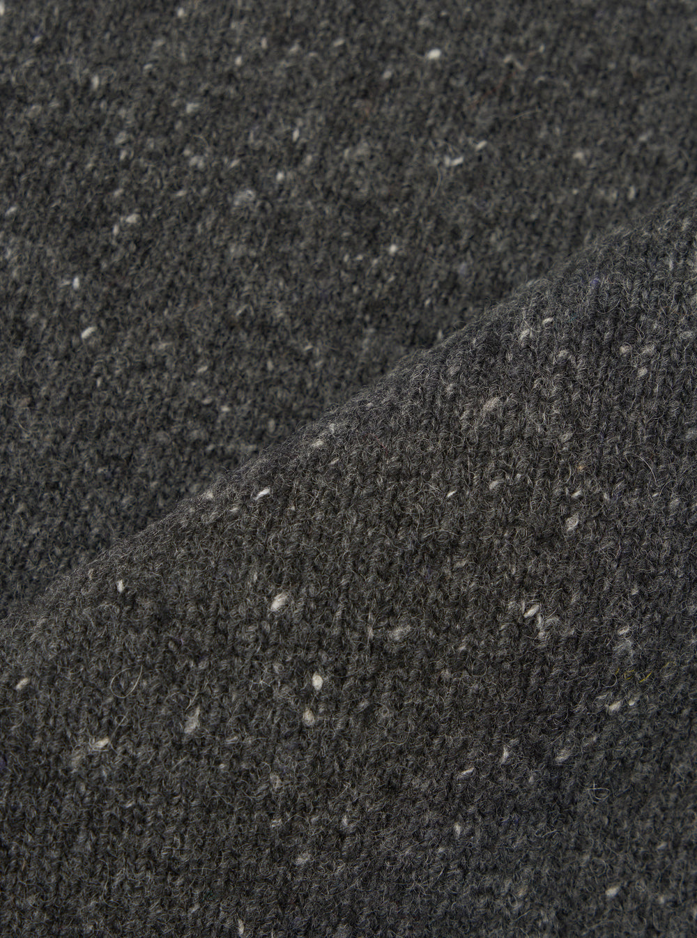 A close-up fabric swatch image of the Black Wool Fleck Sweater Vest material, illustrating the rich black shade, detailed knitted weave, and subtle contrasting fleck accents on a plain backdrop.
