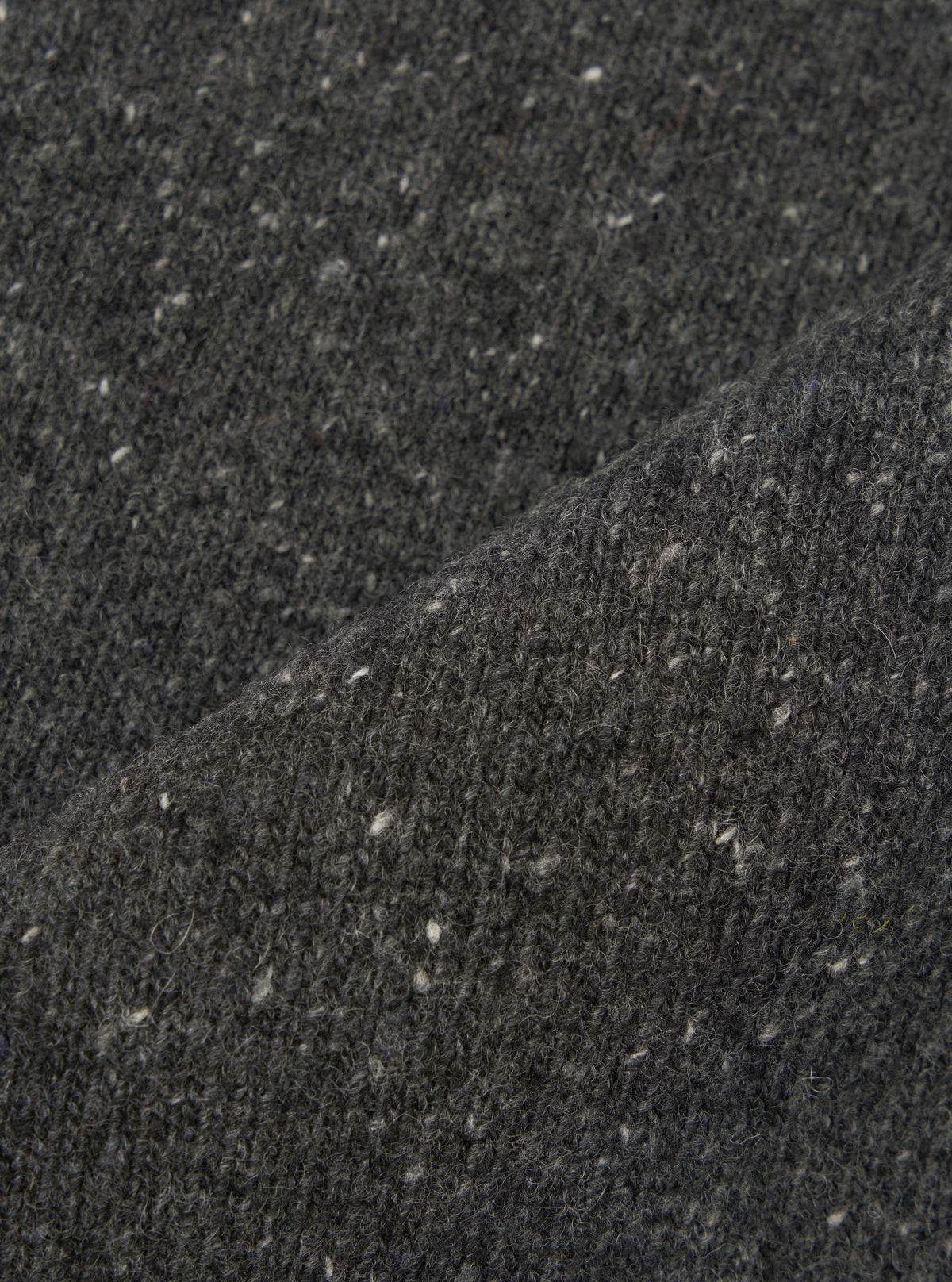 A close-up fabric swatch image of the Black Wool Fleck Sweater Vest material, illustrating the rich black shade, detailed knitted weave, and subtle contrasting fleck accents on a plain backdrop.