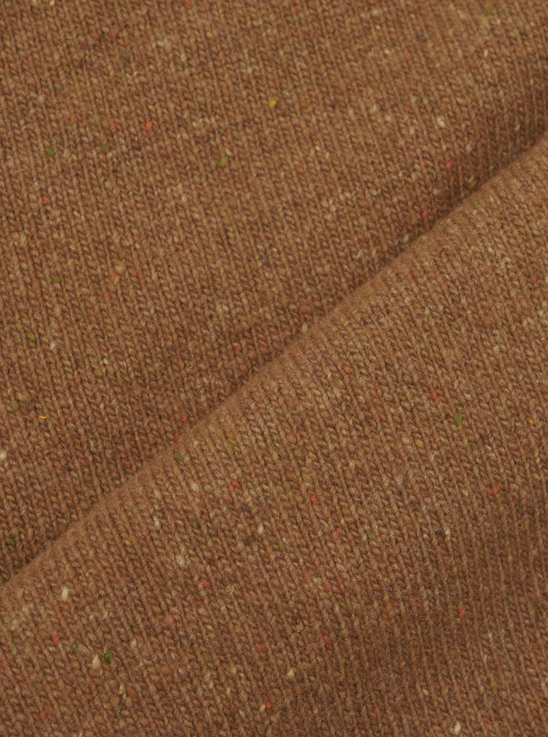 A fabric swatch photograph of the Brown Wool Fleck Sweater Vest on a neutral surface, showcasing the deep brown recycled wool fibers blended with subtle multi-colored flecks throughout the weave.