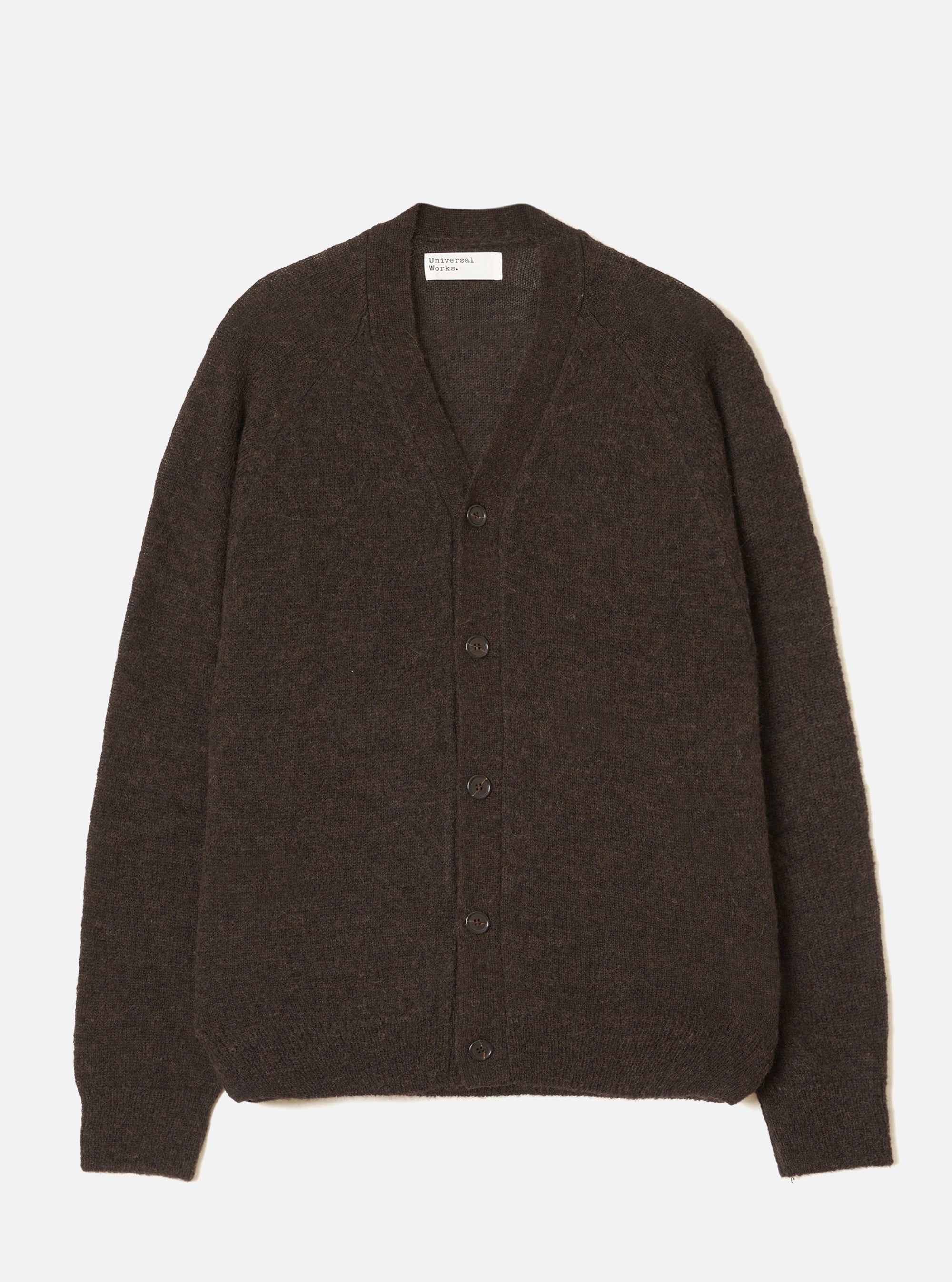 Brown alpaca knit cardigan laid flat on a light grey seamless backdrop. Deep V-neckline with a five-button placket in dark tonal buttons. Raglan sleeves with ribbed cuffs and a ribbed hem. Soft, slightly fluffy knit texture throughout. Universal Works woven label visible at the inner neckline.