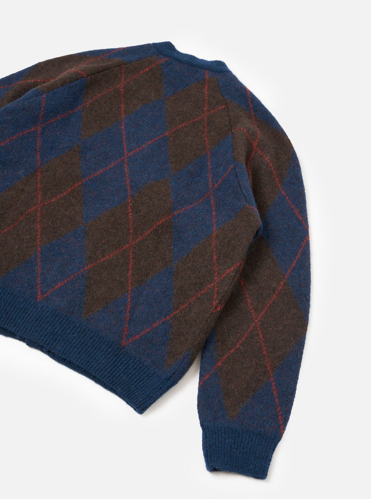 A model wearing the Navy Alpaca Argyle David Cardigan shown from a side angle on a plain background, focusing on the traditional argyle pattern, soft fluffy alpaca fabric, and neat button-front detail.