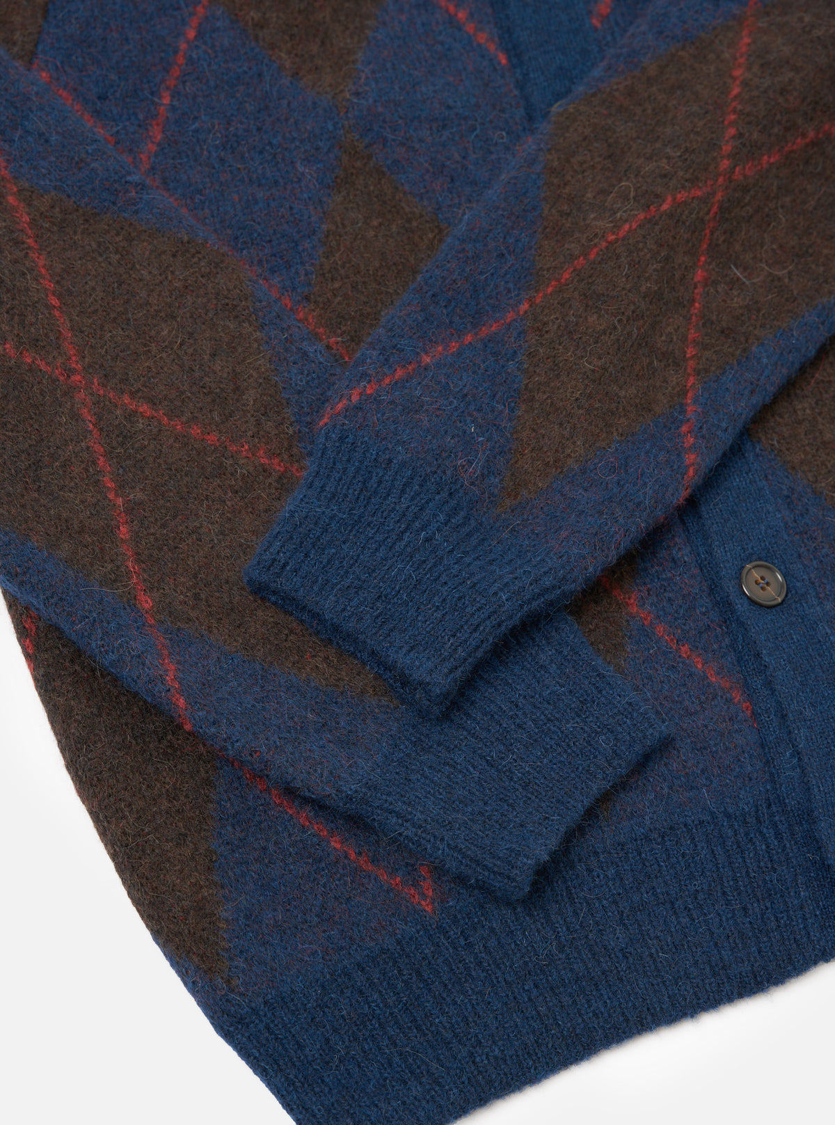 A detailed close-up shot of the Navy Alpaca Argyle David Cardigan, highlighting the intricate geometric argyle pattern, tactile fluffy alpaca blend fibers, and front button closure on a light background.