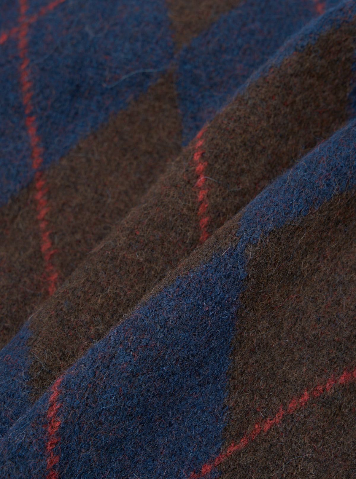 A close-up fabric swatch view of the Navy Alpaca Argyle David Cardigan set against a plain backdrop, highlighting the soft knit texture, argyle pattern detail, and rich alpaca wool blend construction.
