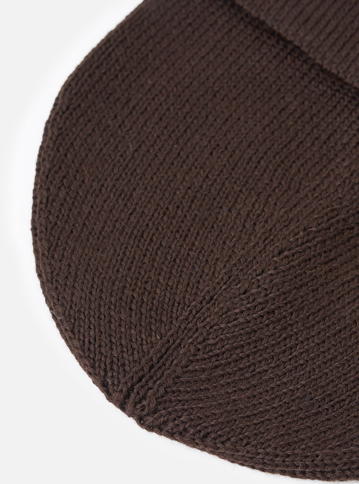 A close-up view of the Brown Merino Knit Watch Cap set against a plain background, focusing on the detailed ribbed knit construction, soft merino wool fibers, and neat finished edging of the turn-up cuff.