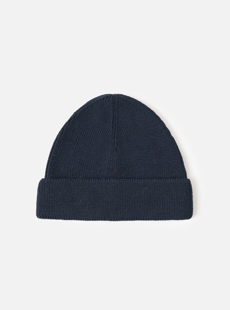 A full view of the Navy Merino Knit Watch Cap displayed against a clean white studio background. The deep navy blue knitted beanie features a thick folded cuff and a classic ribbed pattern throughout.