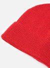 An angled view of the Red Merino Knit Watch Cap isolated on a white background. The description highlights the rich red merino wool fabric, clean stitched seams, and folded ribbed hem of the hat.