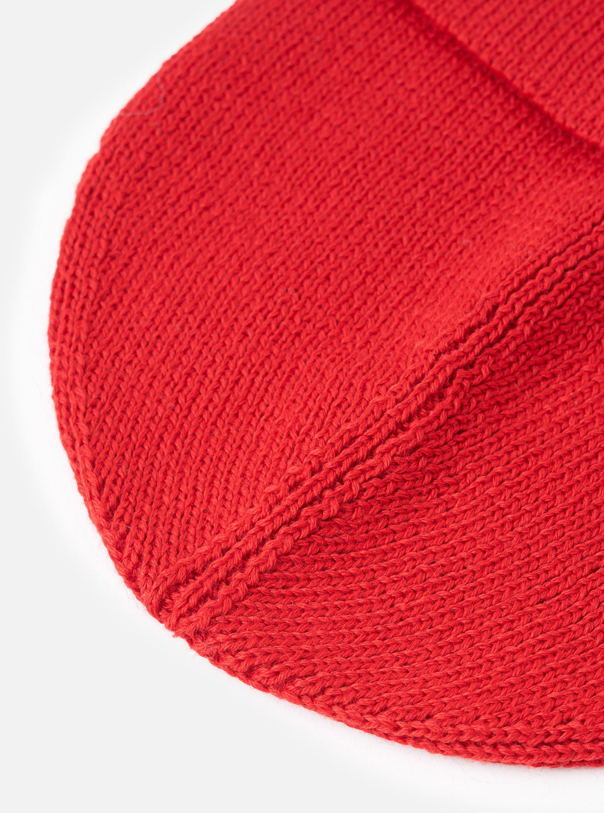 A close-up detailed view of the Red Merino Knit Watch Cap displayed against a clean white background. The image highlights the rich red knitted merino wool texture, fine stitch details, and the folded cuff of the hat.