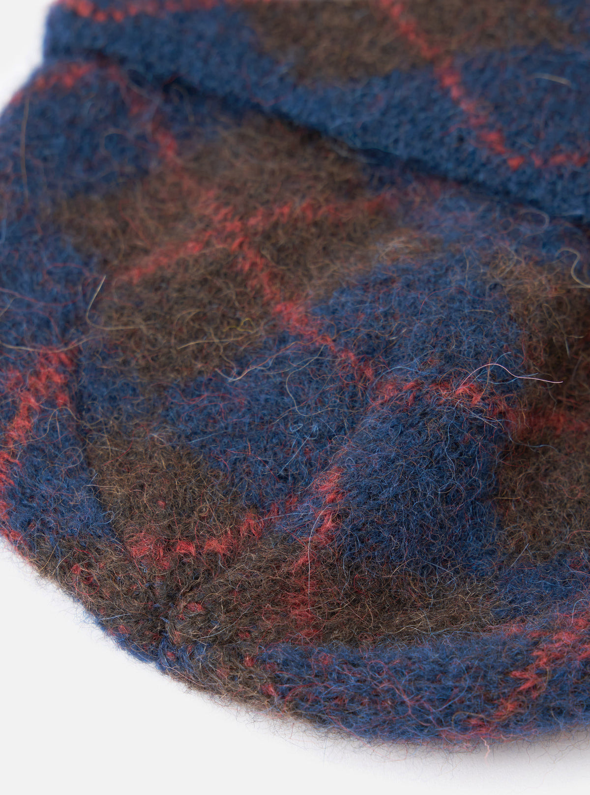A close-up detail shot of the Navy Alpaca Argyle Argyll Hat against a plain white background. The image focuses on the fuzzy alpaca yarn knit fabric, delicate geometric argyle pattern, and finely finished seams around the top crown.