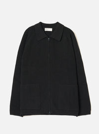 Black ribbed-knit zip cardigan laid flat on a light grey seamless backdrop. Features a spread collar, full-length zip fastening, raglan sleeves, two large patch pockets at the hem, and a wide ribbed waistband. Universal Works woven label visible at the inner collar. No model or mannequin present.