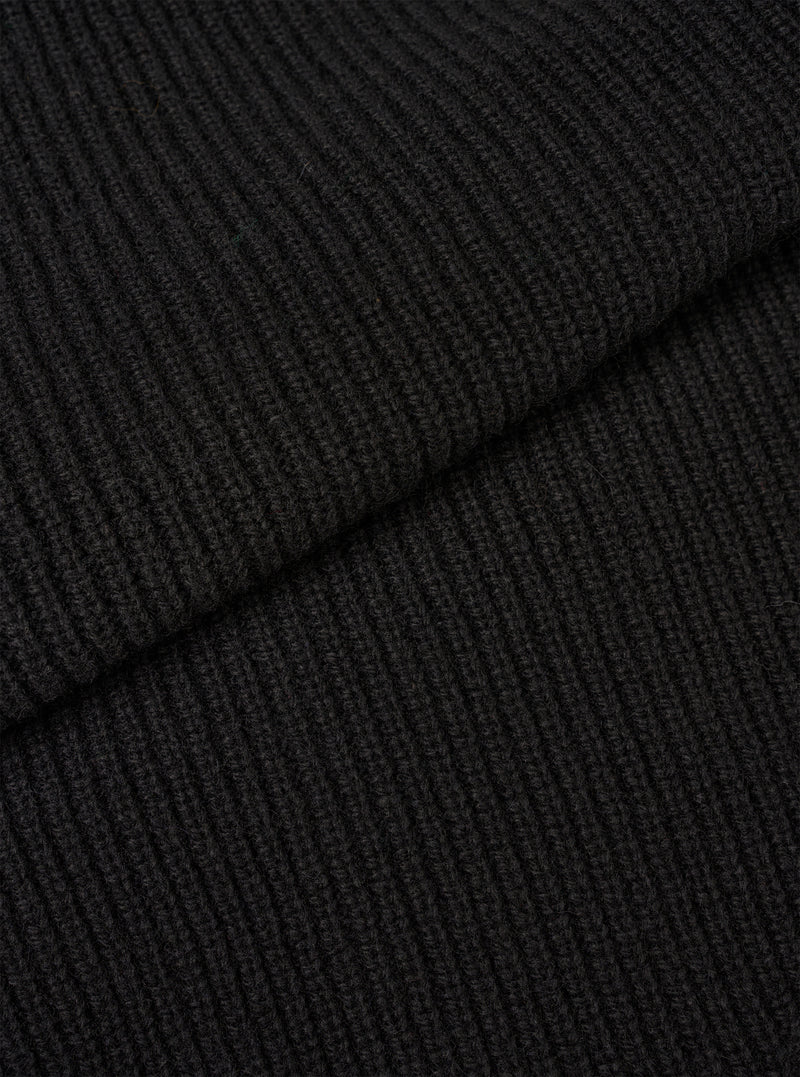 An extreme close-up fabric swatch shot showing the material of the Black Eco Wool Zip Cardigan. The photo details the dense, tactile texture of the black and dark grey eco wool yarn knitted together in a soft, premium weave.