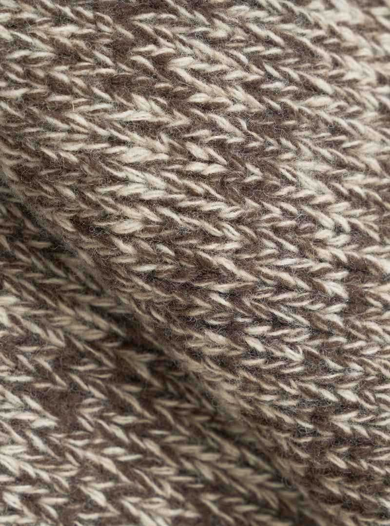 An extreme close-up fabric swatch shot of the Ecru/Brown Lambswool Zip Cardigan. The photo details the thick, warm texture of pure lambswool yarn, showcasing blended ecru and brown fibers knitted together into a soft fabric.