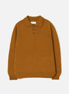 Gold Shetland knit polo sweater laid flat on a white studio backdrop. Features a spread collar, three-button placket with dark buttons, ribbed cuffs and hem, and a chunky plain knit texture throughout. A Universal Works woven label sits inside the collar.