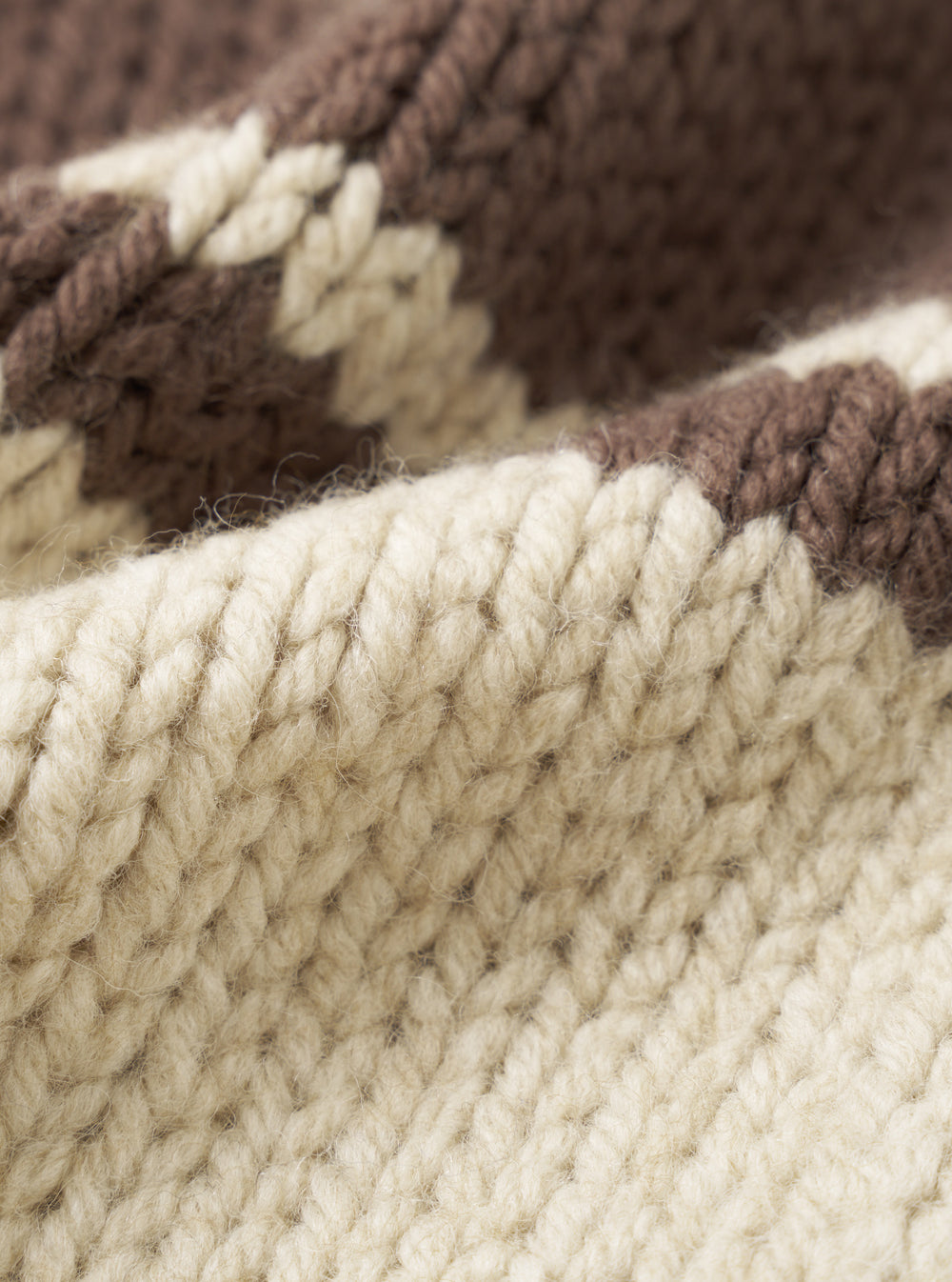 A close-up fabric swatch of the Ecru Chunky Knit Stripe Langdale Cardigan. The detailed shot highlights the rich texture, heavy weave, and contrasting intarsia stripe pattern of the ecru wool yarn against a plain white background.