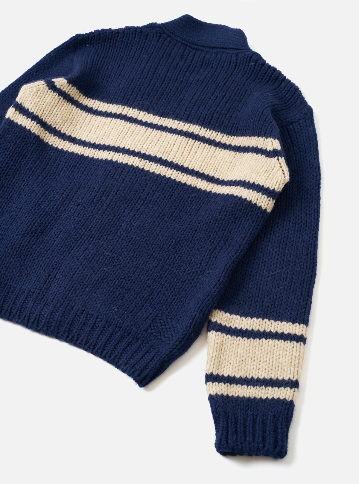 Back view of the Navy Chunky Knit Stripe Langdale Cardigan displayed on a clean white studio background. Features a relaxed fit silhouette with ribbed hem and cuffs, highlighting the continuous striped pattern on navy chunky wool knit.