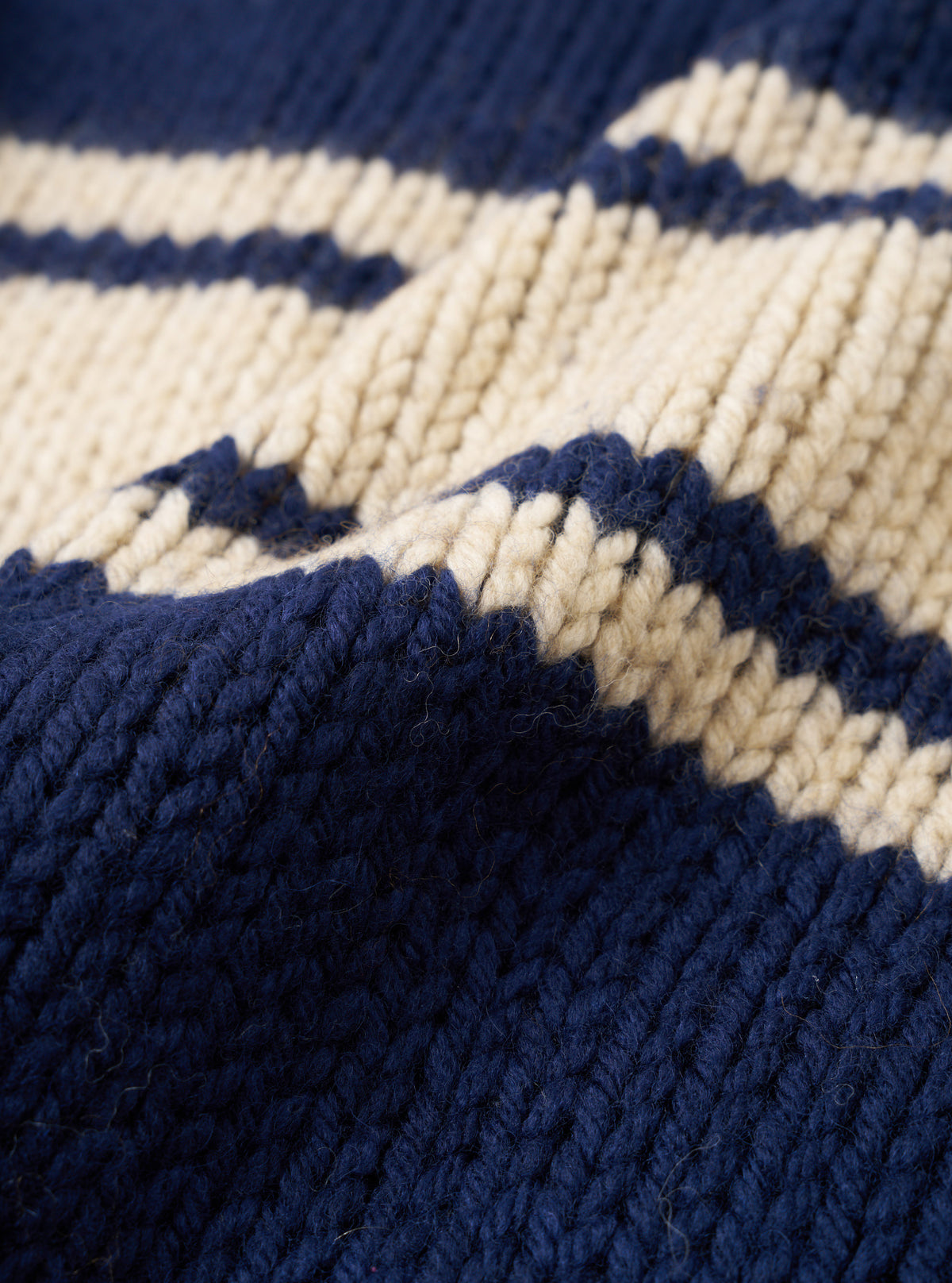 A close-up fabric swatch of the Navy Chunky Knit Stripe Langdale Cardigan. The texture view highlights the dense knit construction, heavy wool yarn, and contrasting intarsia stripe pattern set against a plain white background.