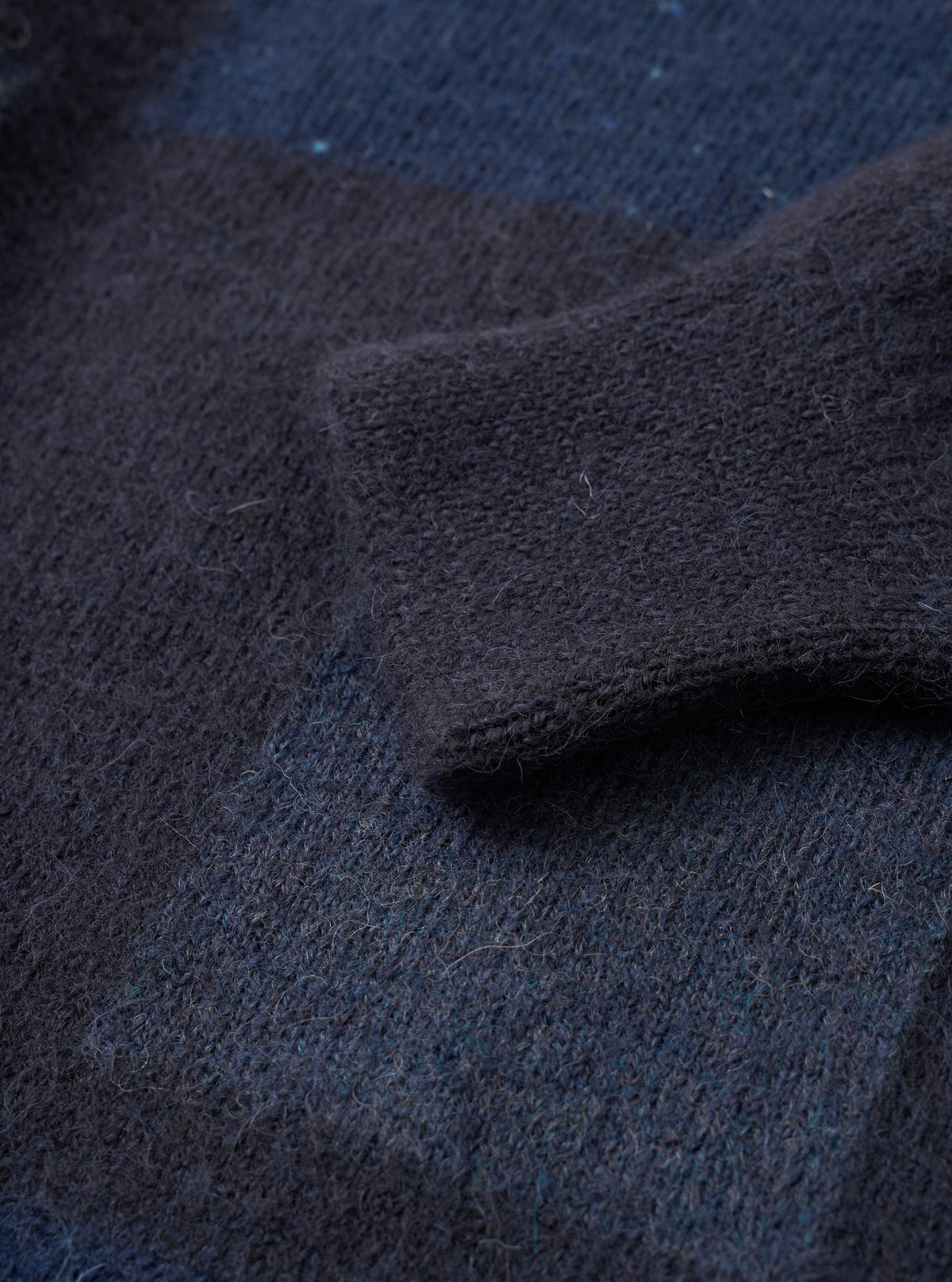 Close-up detail shot of the Navy British Wool Lyon Crew sweater against a plain white background. Highlights the ribbed crew neckline, raglan sleeve stitching, and deep texture of the premium marled navy blue British wool yarn.