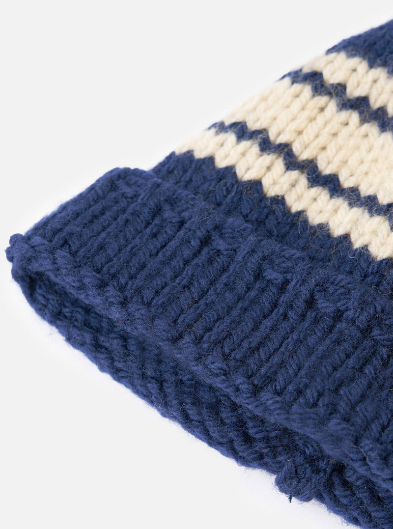 An angled view of the Navy Chunky Knit Stripe Lenny Hat displayed against a clean white background. The image showcases the navy blue knit texture, bold stripe pattern, and folded cuff of the hat.