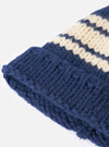 An angled view of the Navy Chunky Knit Stripe Lenny Hat displayed against a clean white background. The image showcases the navy blue knit texture, bold stripe pattern, and folded cuff of the hat.