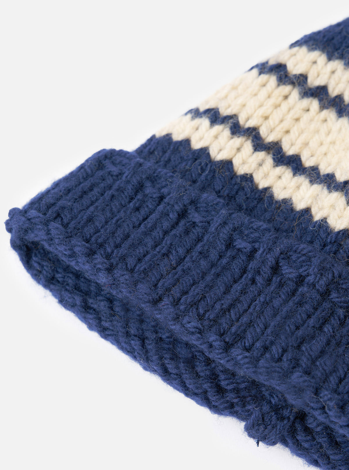 An angled view of the Navy Chunky Knit Stripe Lenny Hat displayed against a clean white background. The image showcases the navy blue knit texture, bold stripe pattern, and folded cuff of the hat.