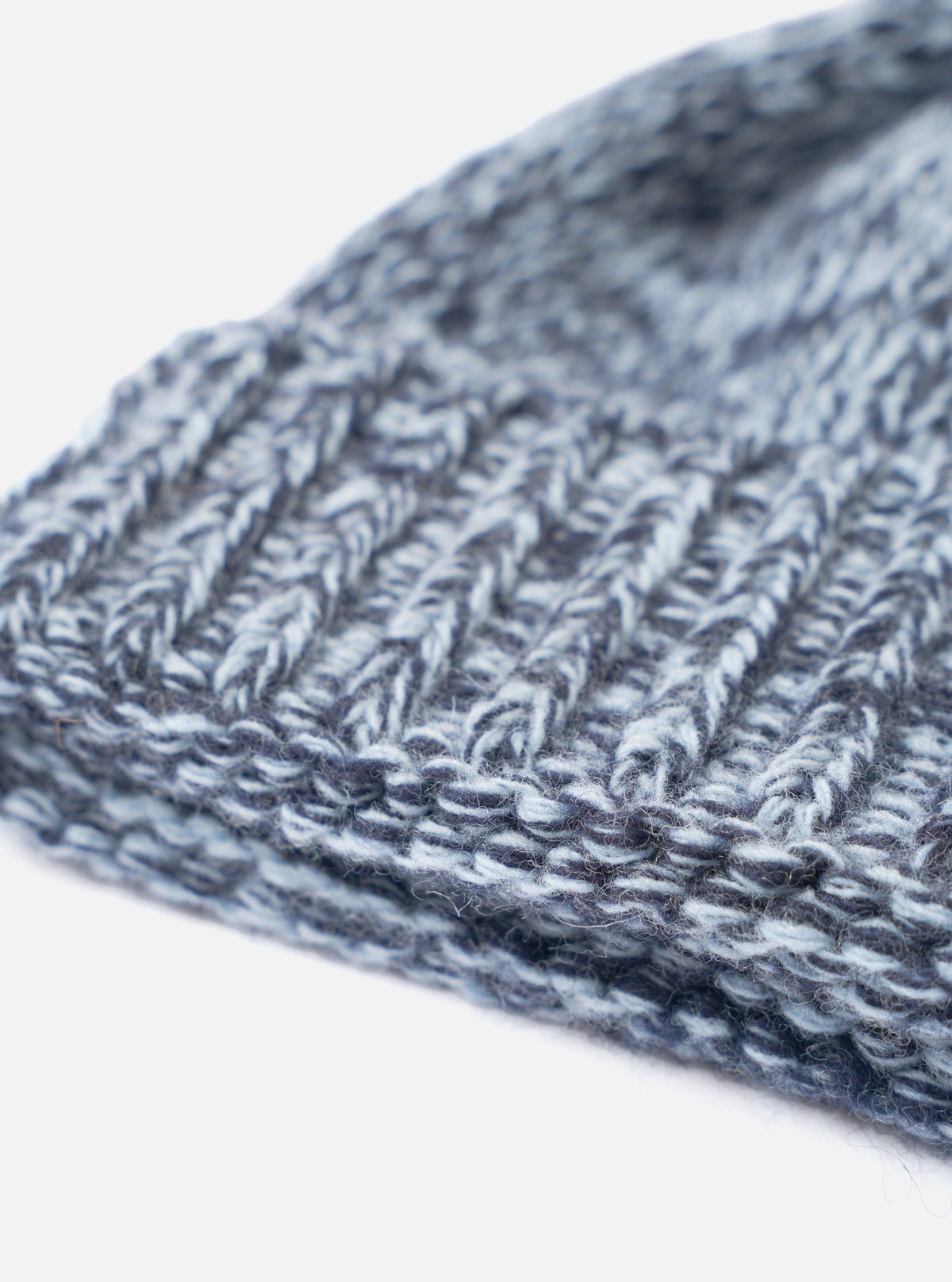 An angled product view of the Sky/Navy Lambswool Watch Cap set on a clean white studio background. The image details the soft lambswool yarn construction, blue shade gradient, and folded cuff.