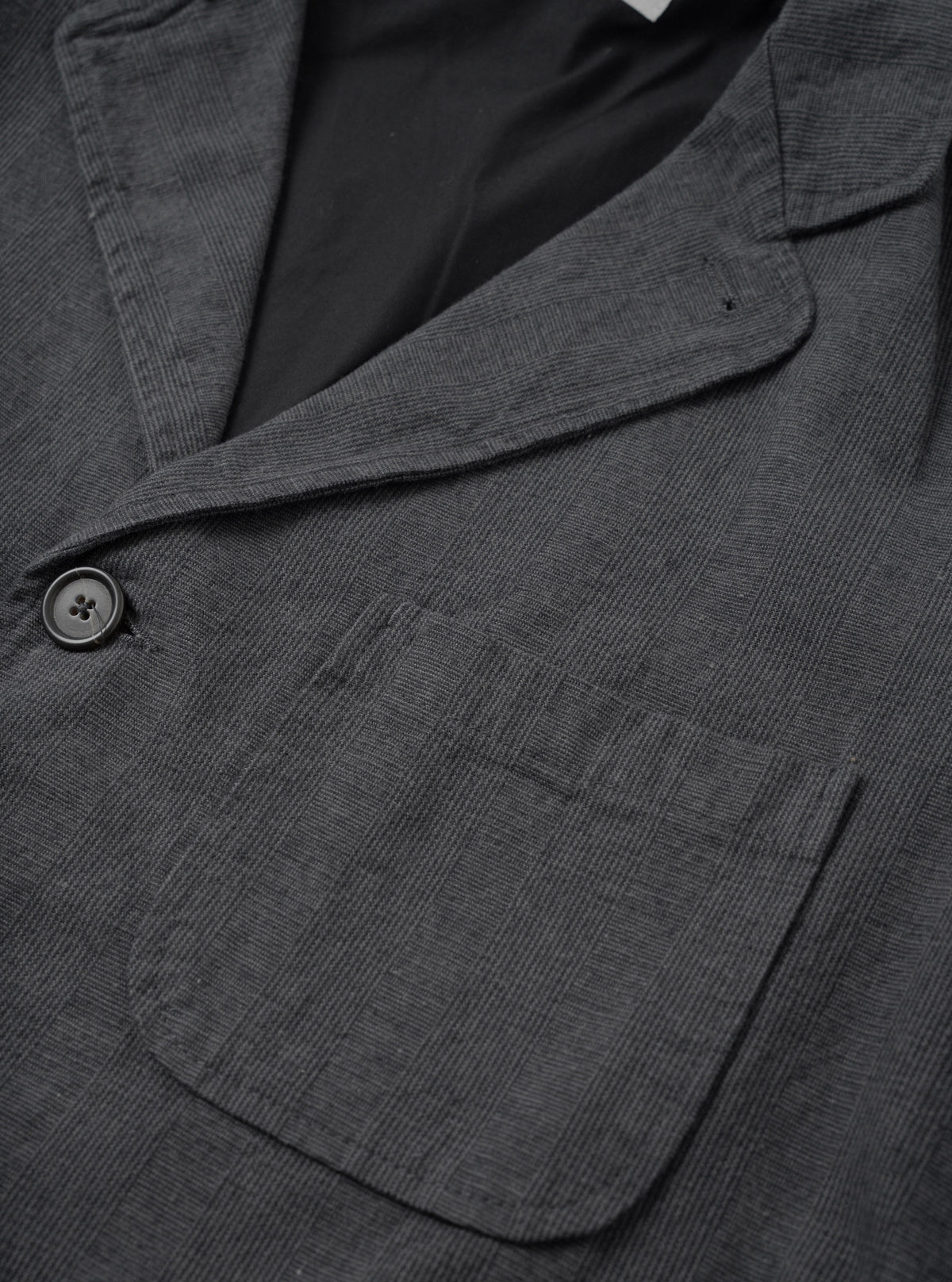 A close-up detail shot of the Grey Liverpool Check Three Button Jacket on a white background, focusing on the three-button front placket, notched lapel stitching, horn buttons, and textured grey cotton-linen check material.