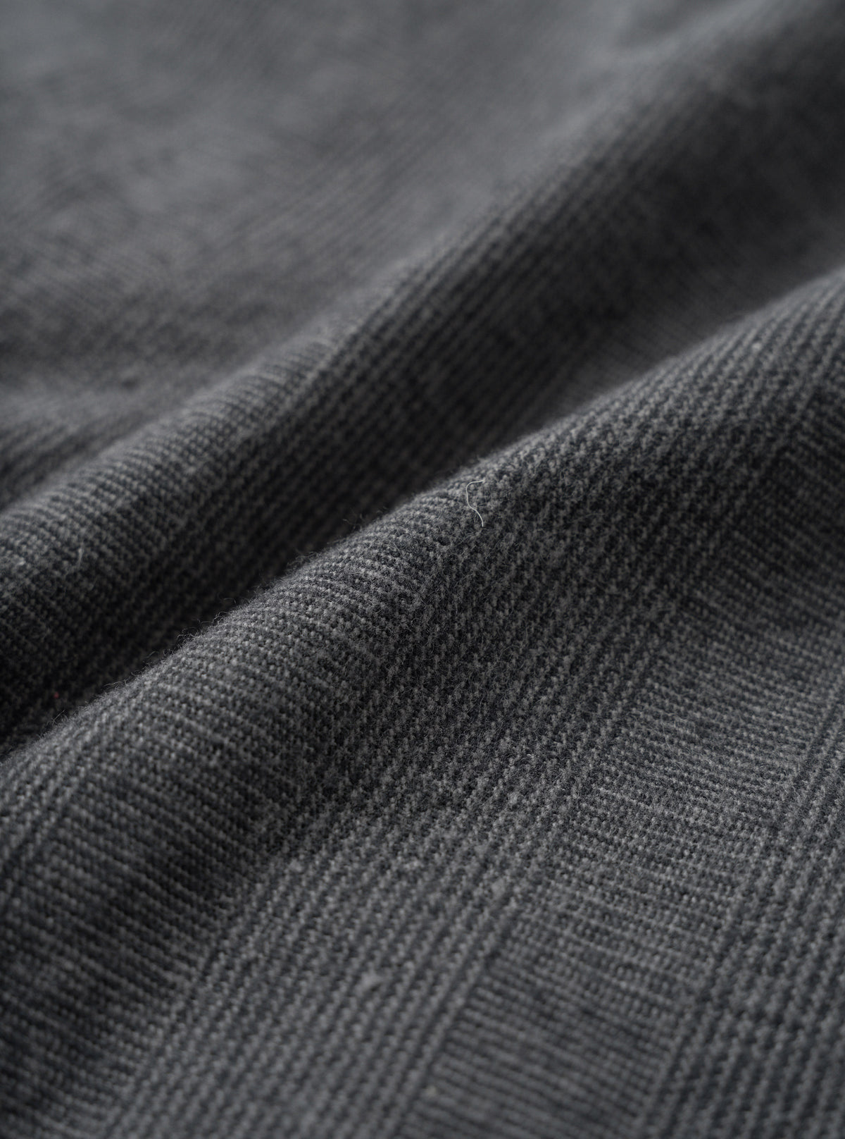 A macro close-up fabric swatch view of the Grey Liverpool Check material against a plain white background, showcasing the fine weave, light grey and dark check pattern, and natural cotton-linen blend texture of the fabric.