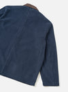 Dark navy corduroy utility jacket, flat lay on a light grey seamless backdrop. Shot shows the back and right sleeve at an angle. Wide-wale cord texture is prominent throughout. A contrast brown corduroy collar is visible at the top. Vertical back seams and a straight hem with visible stitching are shown.