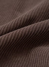A detailed close-up fabric swatch of the Cacao Cord Pleated Track Pant presented on a stark white background, highlighting the distinct fine-wale ridges of the rich cacao brown cotton corduroy fabric.