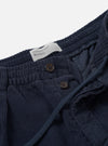 A close-up image showing the waistband and front pleats of the Dark Navy Cord Pleated Track Pant against a white studio background, detailing the dark corduroy texture and drawcord waist closure.