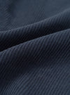 A macro fabric swatch photo of the Dark Navy Cord Pleated Track Pant set against a plain white background, highlighting the soft texture and fine ribbed lines of the navy blue cotton corduroy material.