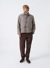 A male model wears the Cacao Cord Military Chino from the waist down in a front view against a neutral studio background, showcasing the straight leg cut, button fly waist, and cacao brown corduroy fabric.