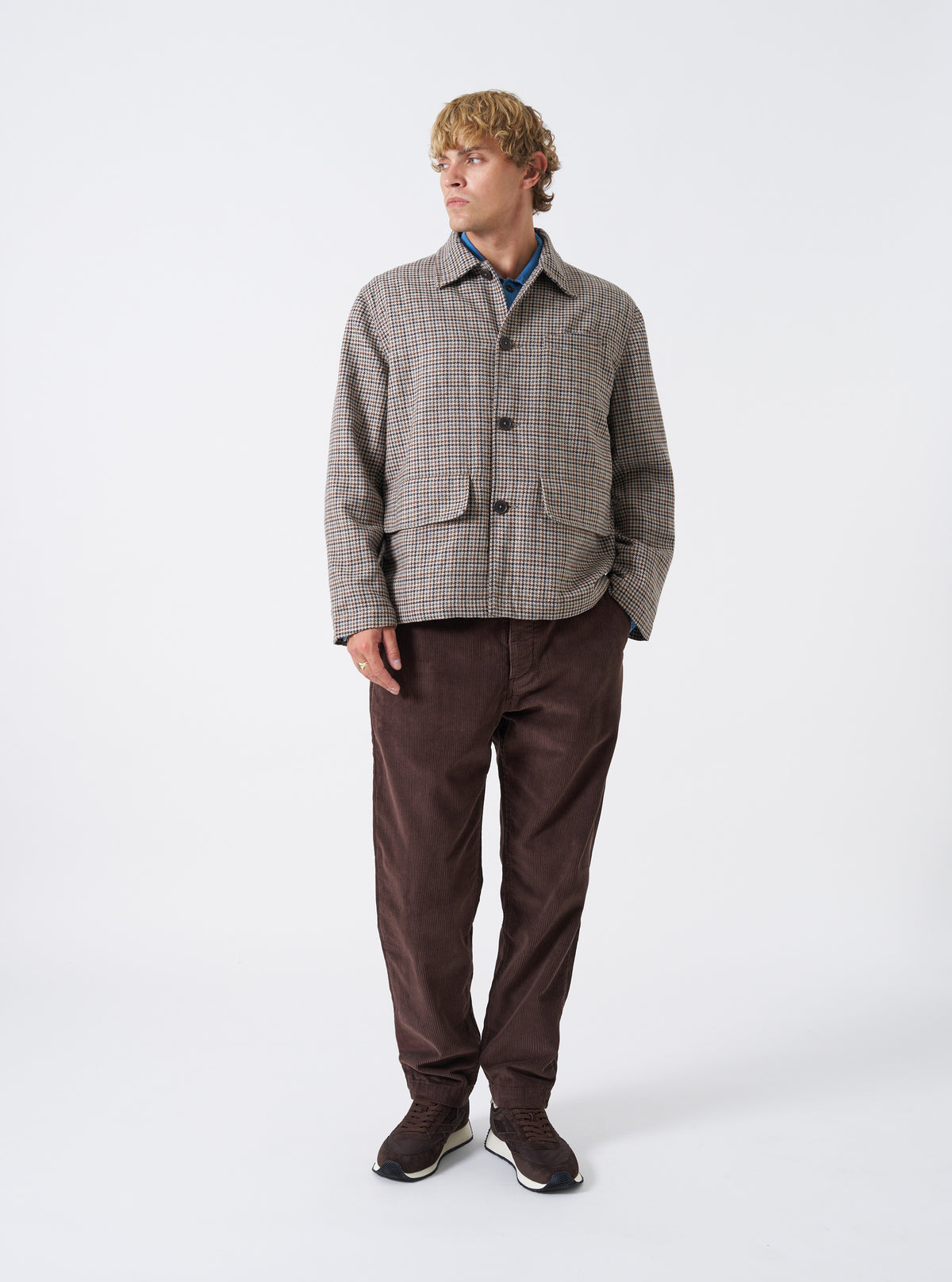 A male model wears the Cacao Cord Military Chino from the waist down in a front view against a neutral studio background, showcasing the straight leg cut, button fly waist, and cacao brown corduroy fabric.