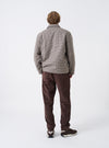 A male model is wearing the Cacao Cord Military Chino shown from a side and rear angle against a plain light background, highlighting the rear pocket placement, slim straight fit, and corduroy material.