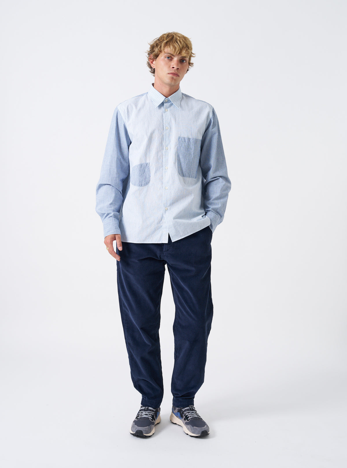 A male model wears the Dark Navy Cord Military Chino in a full front posture on a plain studio background, demonstrating the classic straight-leg cut, front slash pockets, and dark navy corduroy cloth.