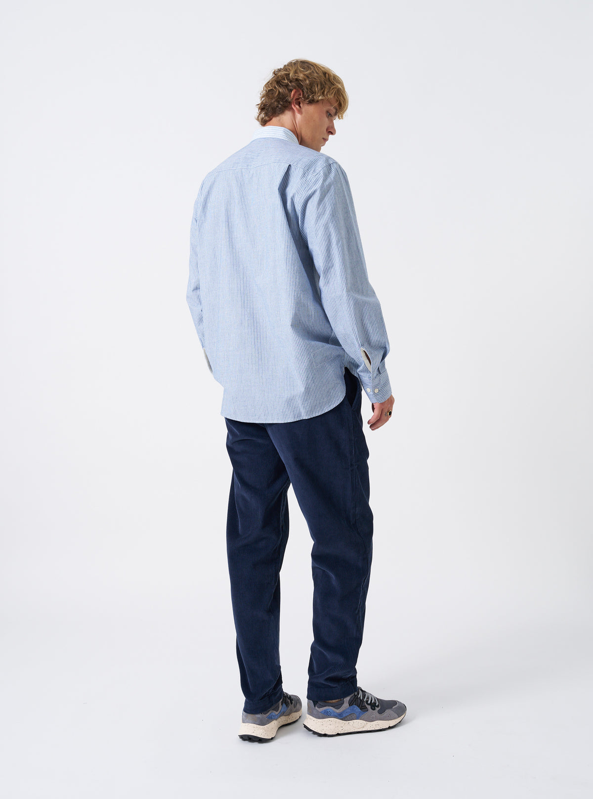 A male model is photographed from behind wearing the Dark Navy Cord Military Chino against a neutral white backdrop, highlighting the tailored seat, rear button pockets, and rich navy corduroy texture.
