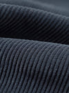 Close-up fabric detail of the dark navy cord military chino, showing wide-wale corduroy texture with raised ridges running diagonally across the frame. Two overlapping layers of the fabric are visible, highlighting the deep navy tone and soft, dense pile of the cord.