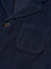 Angled side view of the Dark Navy Cord Three Button Jacket worn by a model against a clean studio background, showing the relaxed fit, sleeve length, notch lapel collar detail, and fine dark navy corduroy texture.