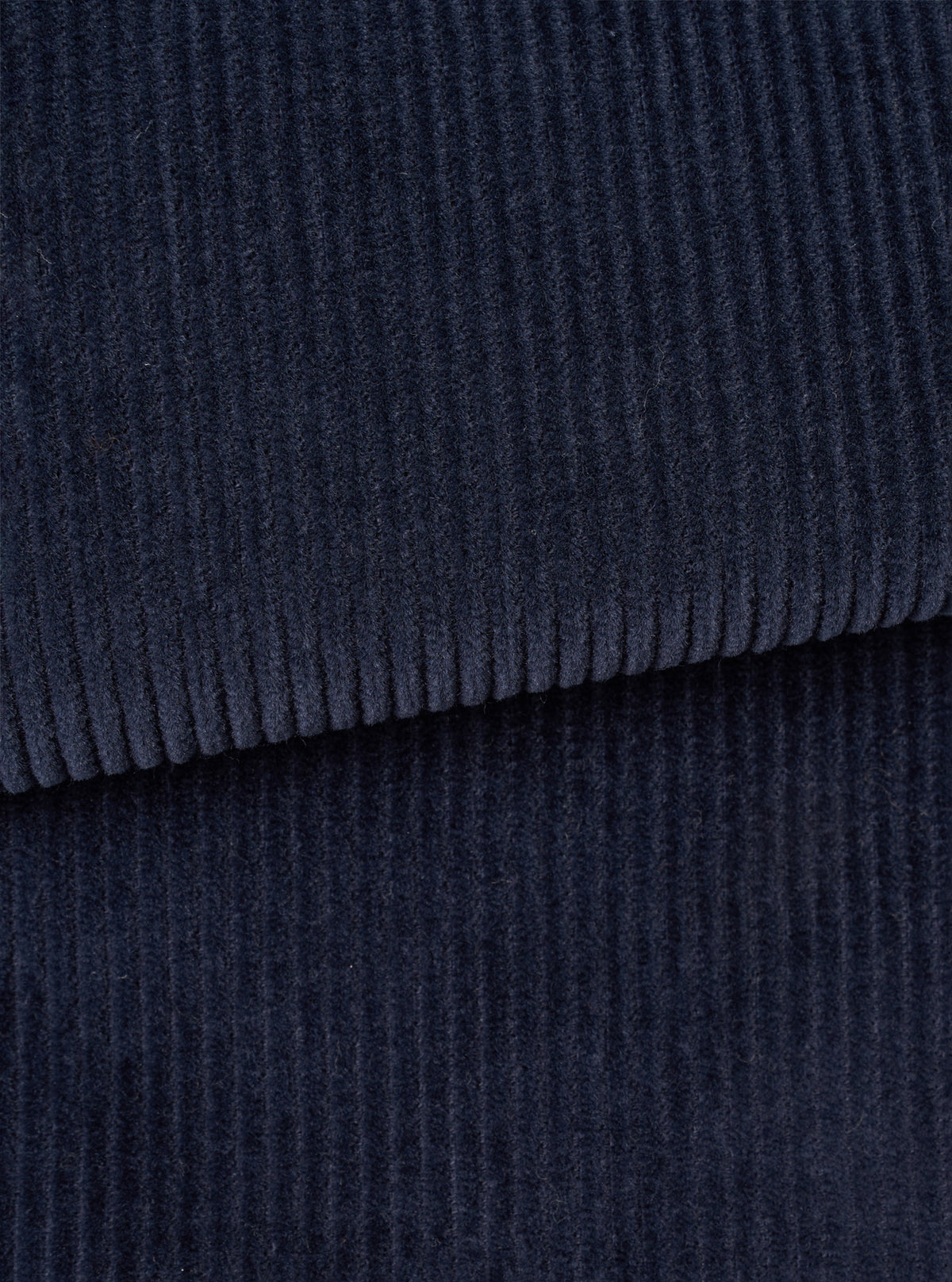 Close-up fabric swatch image of the Dark Navy Cord Three Button Jacket filling the frame. The shot emphasizes the vertical ribbed wale pattern, soft tactile feel, and deep navy blue tone of the cotton corduroy material.