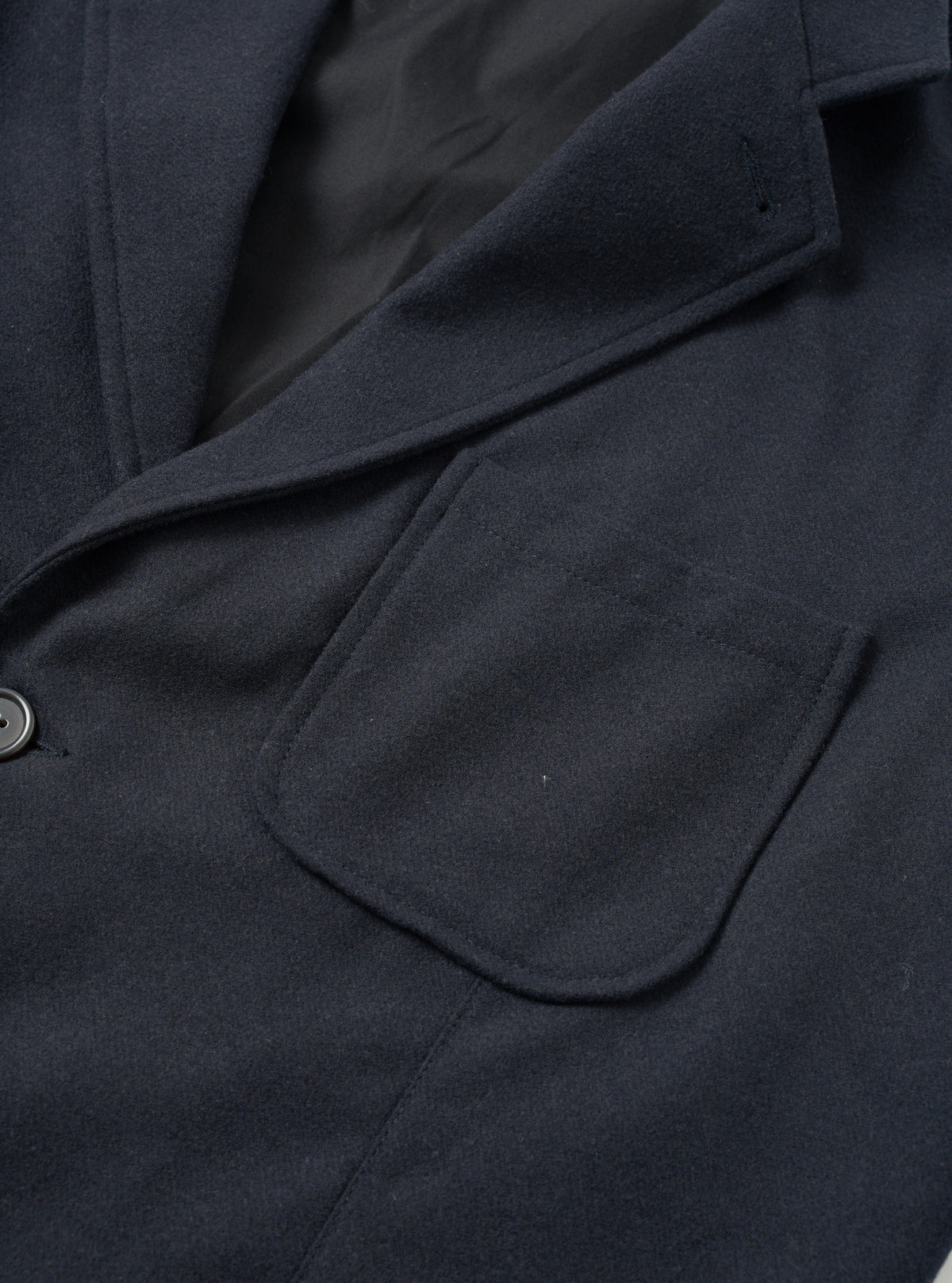 Angled side view of the Dark Navy Dublin Wool Mix Two Button Jacket worn by a model against a plain studio background. The photo focuses on the lapel roll, two-piece sleeve construction, and textured navy wool-blend cloth.