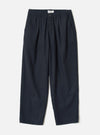 Front view of the Dark Navy Dublin Wool Mix Oxford Pant worn by a model against a plain studio background. The trousers show a wide-leg cut, single front pleats, drawstring waist, and dark navy blue wool-blend fabric.