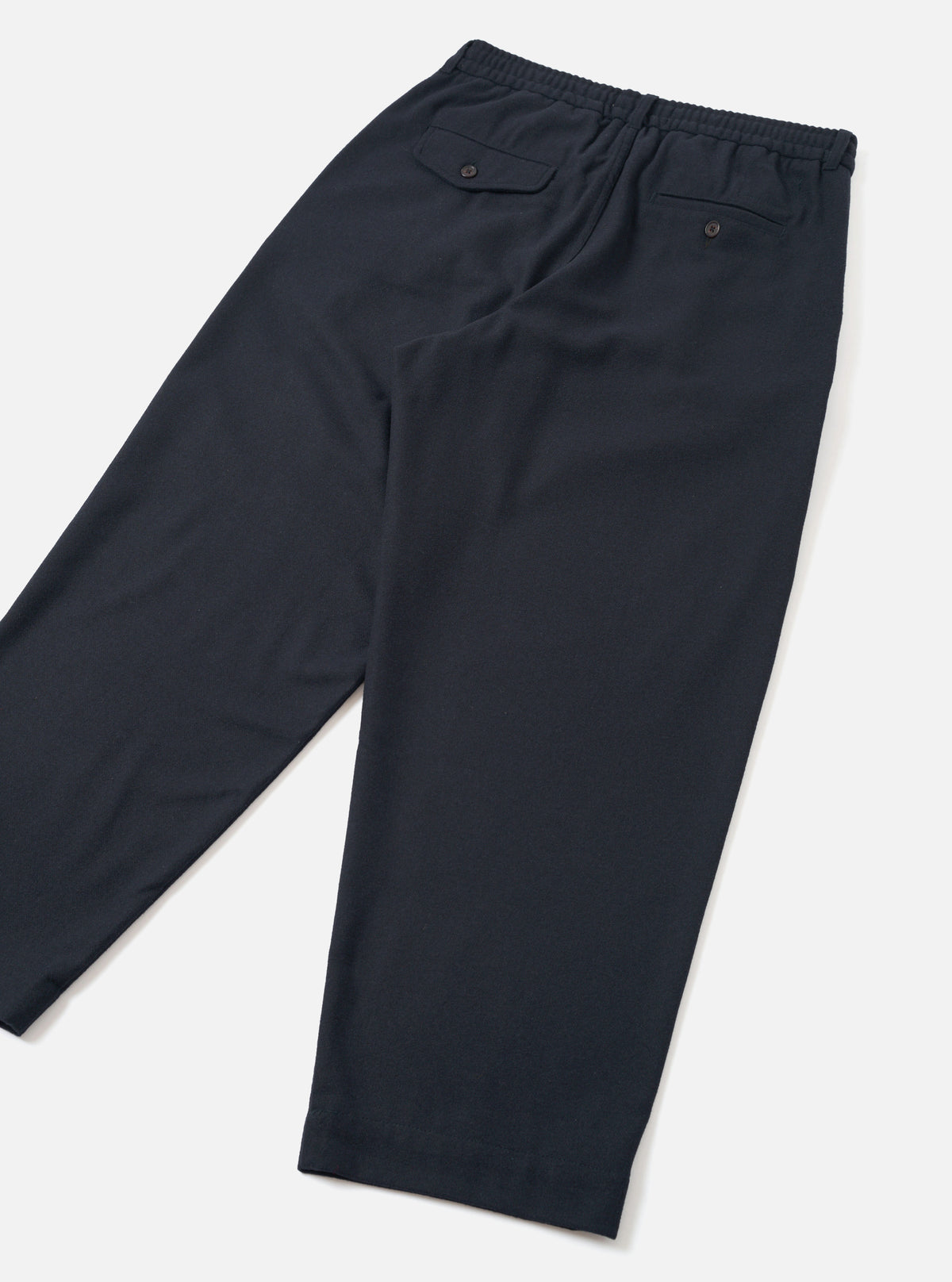 Back view of the Dark Navy Dublin Wool Mix Oxford Pant worn by a model against a clean studio background. The image highlights the rear pockets, relaxed seat, straight leg silhouette, and dark navy textured wool-blend fabric.