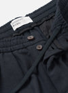 Side view of the Dark Navy Dublin Wool Mix Oxford Pant worn by a model set against a plain studio background. The image showcases the relaxed wide-leg profile, gentle taper toward the hem, and deep navy woven material.