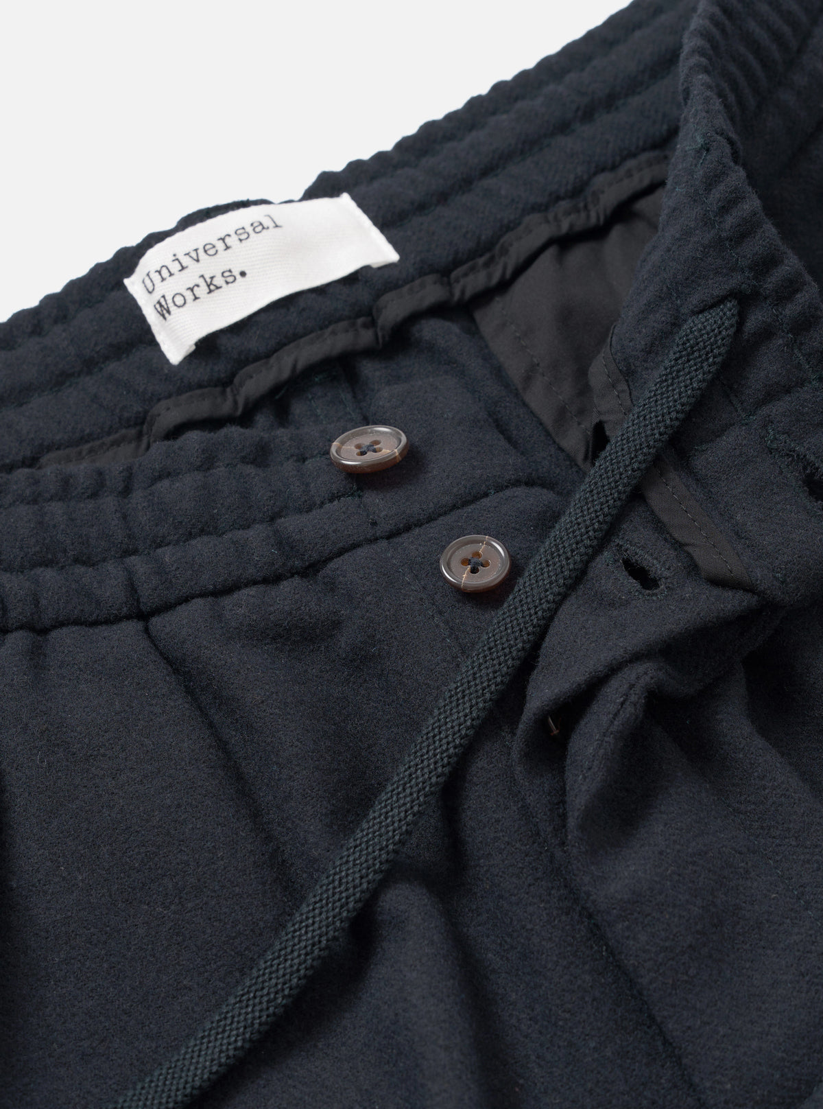 Side view of the Dark Navy Dublin Wool Mix Oxford Pant worn by a model set against a plain studio background. The image showcases the relaxed wide-leg profile, gentle taper toward the hem, and deep navy woven material.