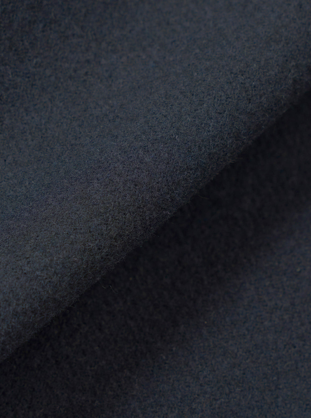 A close-up fabric swatch view showing the intricate weave and soft texture of the Dark Navy Dublin Wool Mix Rose Bowl Jacket. The image fills the frame to emphasize the rich navy color and material quality.