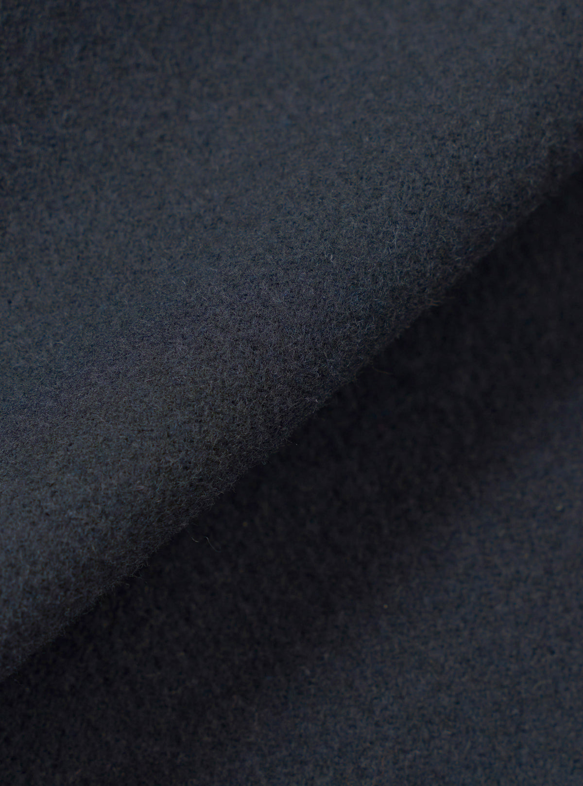 A close-up fabric swatch view showing the intricate weave and soft texture of the Dark Navy Dublin Wool Mix Rose Bowl Jacket. The image fills the frame to emphasize the rich navy color and material quality.
