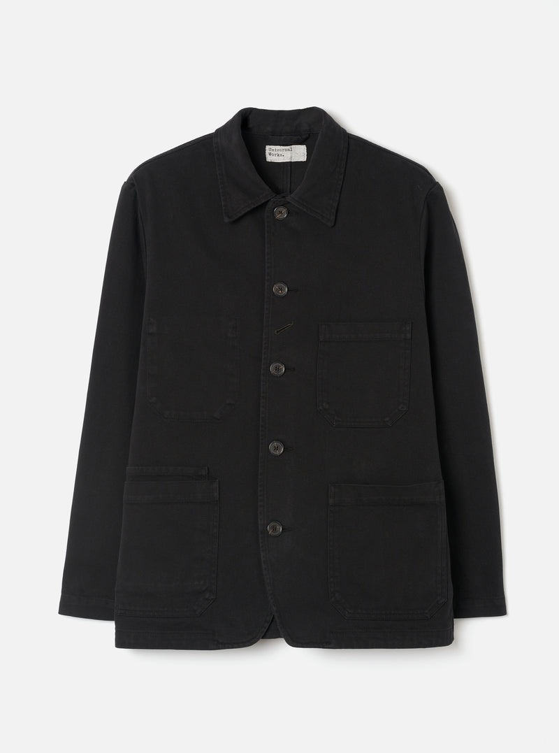 Front view of the Black Dexter Twill OG Bakers Chore Jacket displayed against a plain off-white background. The shot highlights the classic collar, contrast front buttons, and multiple functional patch pockets.