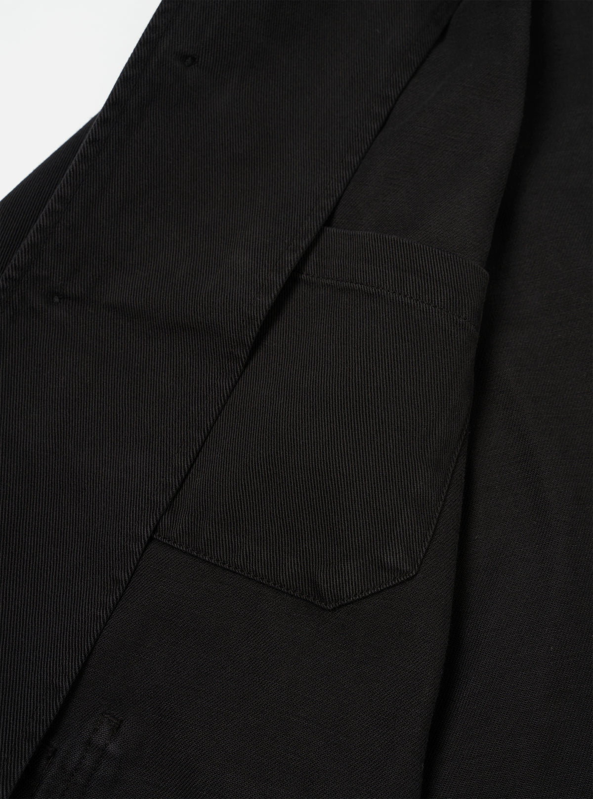 Interior detail view of the Black Dexter Twill OG Bakers Chore Jacket set against a neutral white backdrop. The image showcases the inside hip pocket, interior chest pocket, shoulder lining, and fine seam construction.